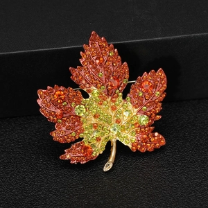 Macro shot of maple leaf brooch with orange and yellow crystals on black leather