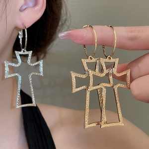 Detailed view of hollow cross pendant hoop earrings in gold and silver finish