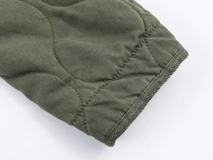 Detailed close-up of army green quilted cotton jacket with wave stitching and twill texture