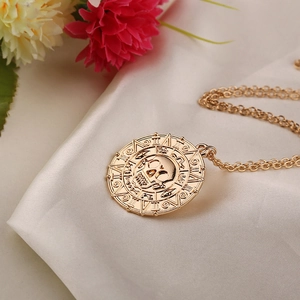 Vintage gold skull medallion necklace with Roman numerals on elegant white fabric