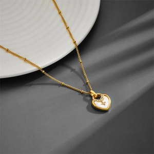 Detail of gold heart pendant with white mother of pearl and V-shaped pave diamonds