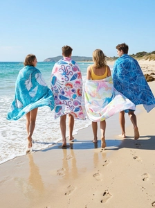 Four different beach towels featuring vibrant ocean patterns shown on a sunny beach