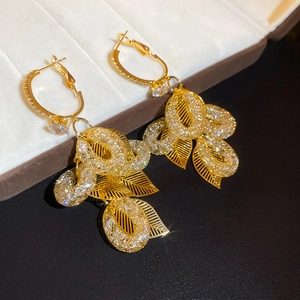 Detailed close-up of golden leaf tassel earrings with sparkling zircon on velvet