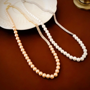 Elegant gold plated necklace with pearls and zircon crystals shown on a white ceramic plate