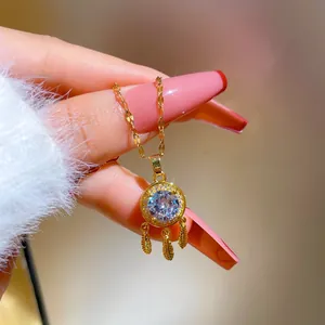 Detailed close-up of a gold dreamcatcher pendant featuring zircon stones and feathers