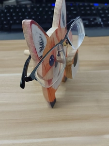 Detailed view of hand-painted wooden fox glasses holder on a home office desk