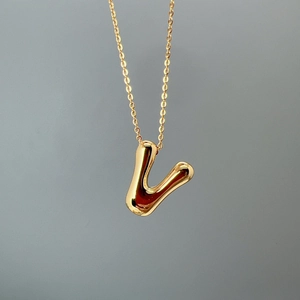 Macro shot of a polished gold letter V pendant on a delicate O-chain necklace