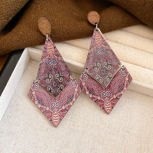 Close-up of bohemian diamond-shaped printed wooden pendant earrings on a linen tray