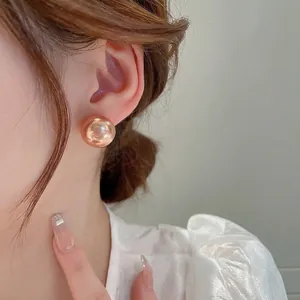 Elegant rose gold spherical pearl stud earrings on a model with a minimalist aesthetic