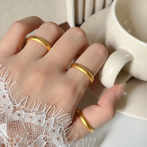 Matte gold minimalist rings shown on fingers holding a white coffee cup with lace detail