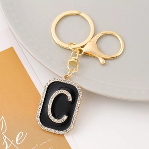 Macro detail of golden letter C keychain with black enamel and sparkling rhinestones