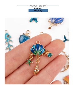 Close-up of blue enamel mermaid shell charms with golden starfish and conch detail