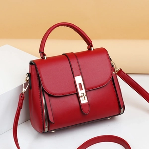 Retro red leather crossbody bag with top handle and gold twist lock in side view
