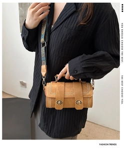 Close-up of brown retro Boston bag featuring white stitching and embroidered wide strap