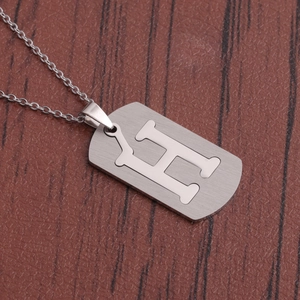 Gros plan d'un collier en acier inoxydable argenté avec pendentif lettre H évidé