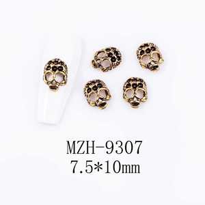 Detailed view of skull nail charms in antique bronze finish on white nail tips