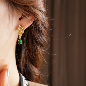 Détail de boucles d'oreilles fleurs vintage plaquées or avec pierre ovale verte