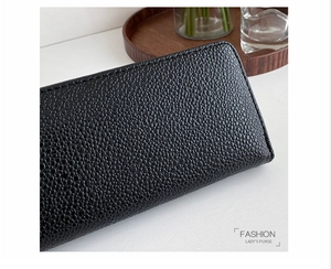 Detail of black caviar texture leather and fine stitching on a long zip wallet