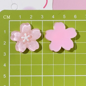 Detailed view of 2.5cm cherry blossom resin charms for DIY crafts on a measuring mat