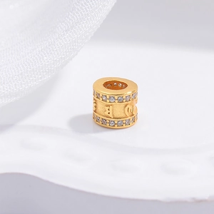 Macro detail of gold-plated S925 silver bead charm with cubic zirconia and sacred engraving