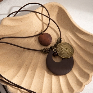 Detail of bohemian layered necklace with brown wood, leather pieces and bronze spiral pendant