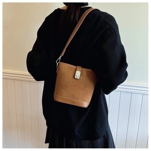 Detail of brown suede bucket bag with leather base and adjustable crossbody strap