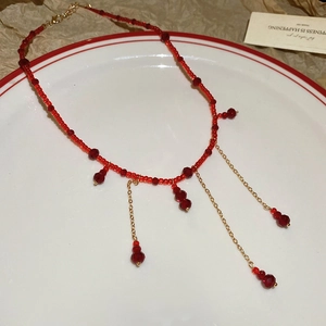 Detail of red crystal beaded tassel necklace with gold chains on a decorative plate