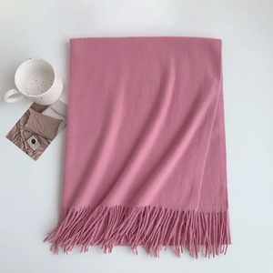 Detail view of the soft pink cashmere-like fabric texture and fringe on the scarf