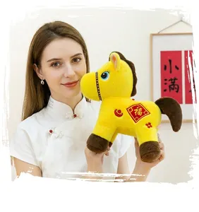 A young woman holding a soft yellow plush horse mascot decorated with traditional symbols