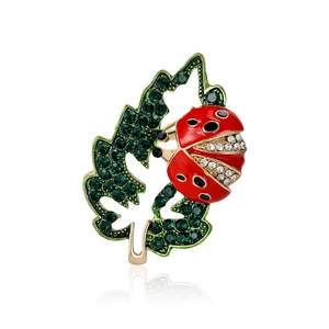 Rhinestone ladybug on green leaf brooch with gold metal base and enamel finish