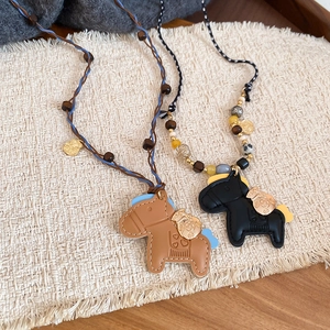 Detail showing faux leather pony charms with white stitching and wooden bead accents