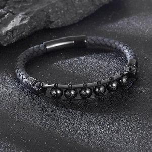Detail eines schwarzen Lederarmbands mit sechs Metallperlen auf dunklem Mineralhintergrund