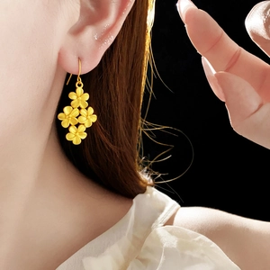 Gros plan de boucles d'oreilles fleurs plaquées or 18 carats sur un mannequin fond noir