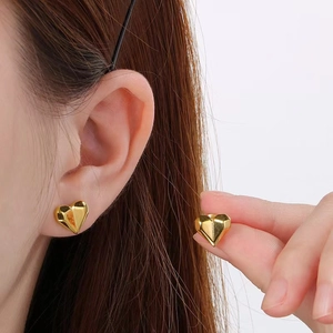 Polished 18k gold plated stainless steel 3D heart stud earrings worn by a model