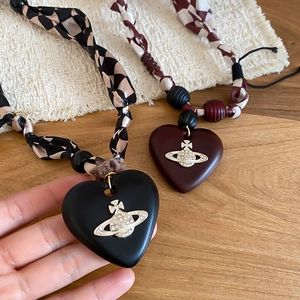 Detailed close-up of a vintage heart pendant necklace with checkered fabric strap