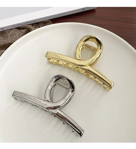 Close-up of gold and silver minimalist metal shark hair clips on a white plate