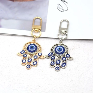 Detailed close-up of gold and silver Hamsa hand keychains with blue evil eyes and rhinestones