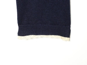Close-up of navy knit cardigan featuring delicate off-white lace trim on the cuffs