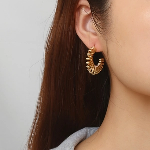 Boucles d'oreilles créoles dorées en spirale pour femmes portées pour un look tendance