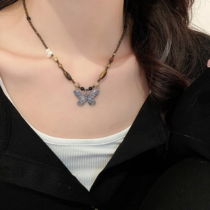 Close-up of beaded necklace featuring a silver butterfly pendant on a beaded strand