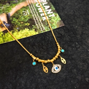 Detail of gold evil eye necklace with turquoise charms and crystals on a black background