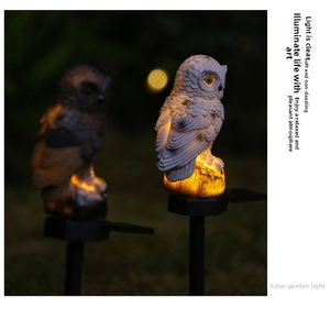 Close-up of owl solar light resin texture with warm LED glow in a dark night garden