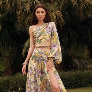 Detail of floral one-shoulder jumpsuit with gold chain belt and tropical print