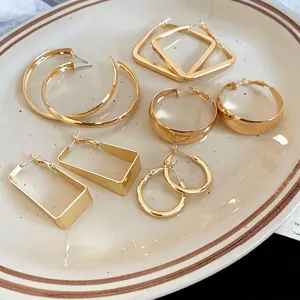 Polished gold geometric hoop earring set featuring round and square designs on a tray