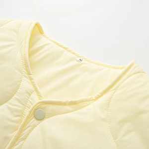 Detail view of pale yellow quilted jacket collar showing fabric texture and size S label