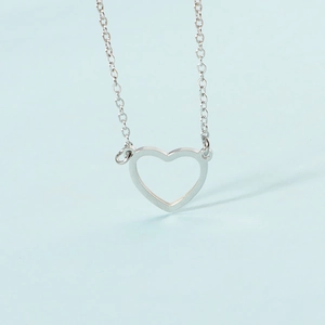 Close-up of minimalist silver hollow heart pendant on a delicate chain necklace