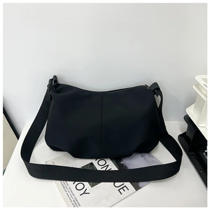 Macro shot of matte black minimalist crossbody bag on a white desk with aesthetic magazines