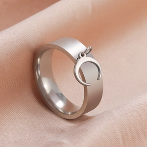Minimalist silver wide band ring with crescent moon pendant on pink silk background