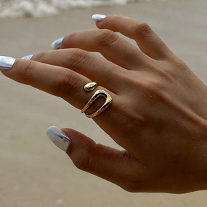 Close-up of a gold geometric open ring on a finger with a high-polished finish