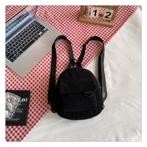 Detail of black corduroy mini backpack texture on a casual home office desk setting